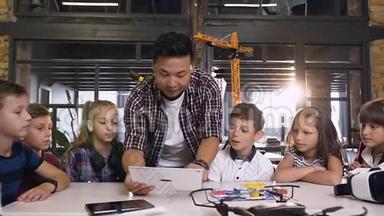 六个年轻的白种人好奇的技术人员和他们的老师一起在工程中使用电脑平板电脑